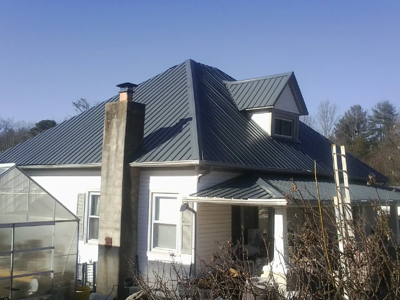 Dark blue standing seam metal roof on a white farmhouse with dormer — Slate & Tile Roof Repair by Roofing Brothers in Halifax