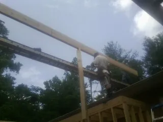 Carpenter setting a ridge beam over a new addition frame — Ice Dam Removal by Roofing Brothers in Halifax